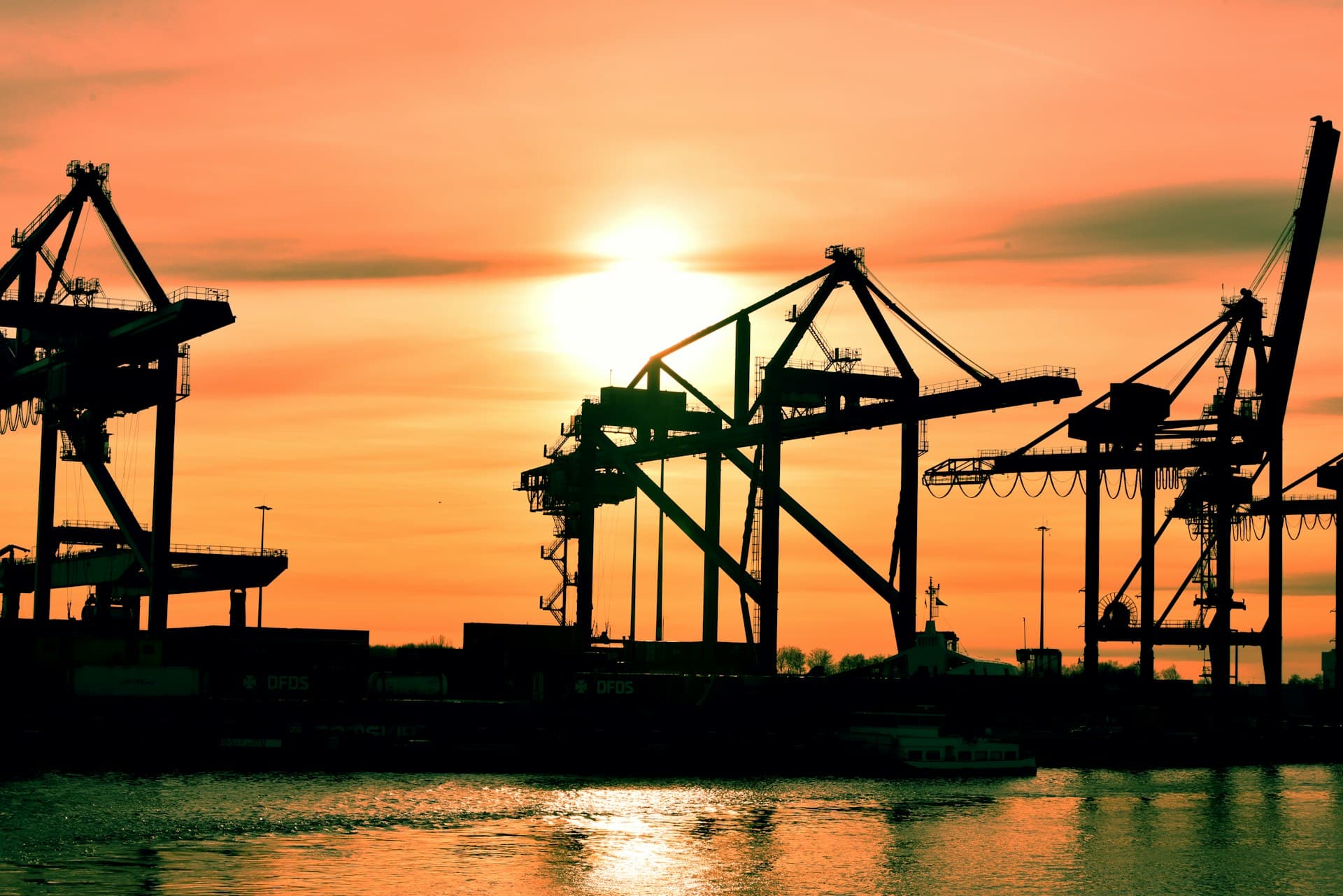 Large gantry cranes at a port beside a wind turbine
