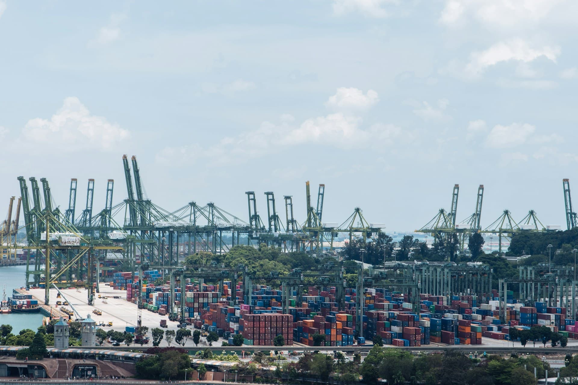 Container ship beneath red gantry cranes in a busy harbor